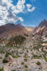 The beautiful mountain trekking road with clear blue sky and rocky hills and the view of Alaudin lake in Fann mountains in Tajikistan