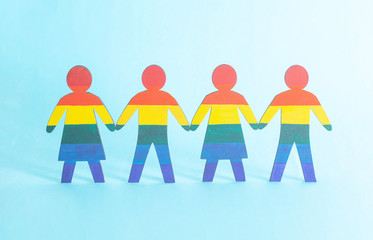 Wooden figurines painted in the color of the LGBT flag. The concept of lesbians among girls and gays among men, background