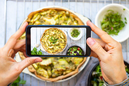 Make picture of vegan food with phone. Smartphone blogging photography of zucchini potato vegetables casserole.