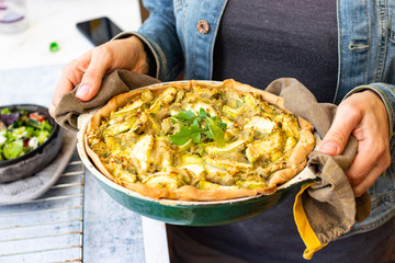 Vegetable casserole or tart with potato and zucchini. Vegan healthy food. Woman hands