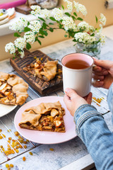 Woman hold cup of hot tea. Breakfast with baked apple pie, cake, or tart sweet vegan dessert on plate. 