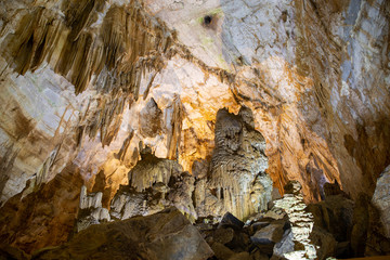 Stalactites hanging from the roof and sides of a cave colored yellow by impurities
