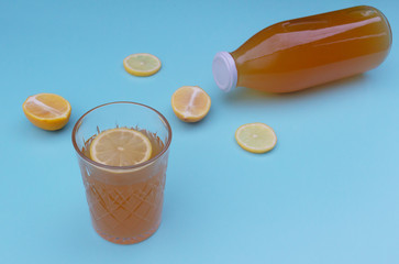 Kombucha with lemon in a glass bottle and a glass on a blue background