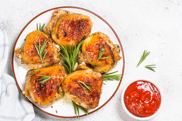 Baked chicken thighs with herbs on white plate.