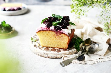 Cake with cream and blackberries on the plate on a gray background, still life