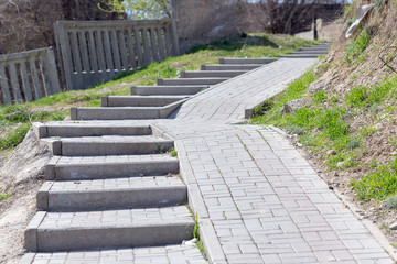 Stone steps on the sidewalk to climb the upper road