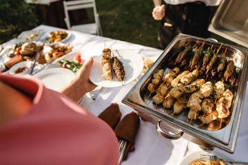 A beautiful decoration of the wedding buffet table outdoors with sweets, fresh flowers on wooden...