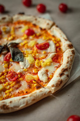 Pizza closeup with chicken, tomatoes, pineapple, cheese on Kraft paper or wood. Fresh pizza.