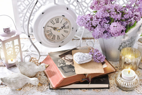 vintage style home decoration with bunch of purple lilac blossoms and old books