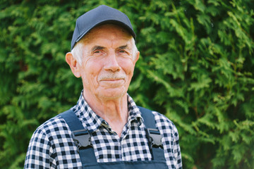 Naklejka na ściany i meble Senior professional worker in overall and cap. Aged farmer. Old craftsman. Close up