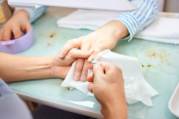 Obraz na płótnie Canvas man make hygienic manicure in a beauty salon. A hand holding a piece of paper. High quality photo