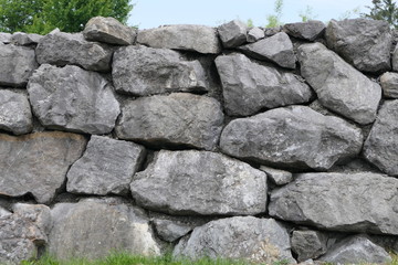 Mighty stone wall of grey granite with big massive blocks, stony texture