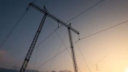 Silhouette of high voltage electric power tower at beautiful sunset with dramatic clouds