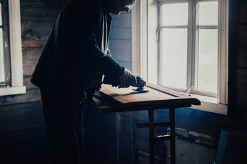 elderly man polishes a wooden board with a grinder at home. Furniture restoration, housework.