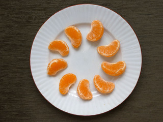 Few peeled tangerine slices on white plate like sunbeams