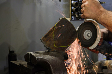 Worker without protective gloves cutting steel sheet an electric wheel grinding machine