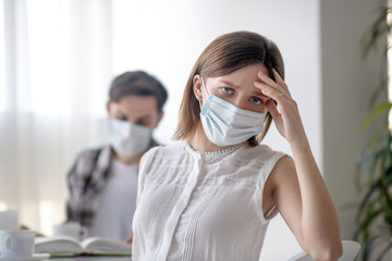 Young woman in a facial mask having a headache