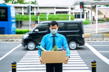 Unhappy businessman carries a box while cross road