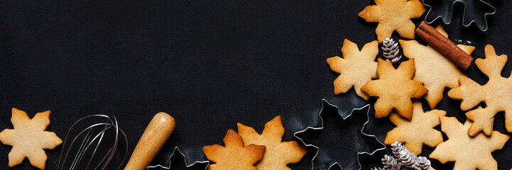 Christmas composition with homemade gingerbread cookies, molds. Family time, preparing for holiday season. Festive mood. Flat lay top view, dark black background, copy space. Banner