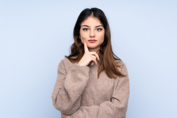 Young brunette woman wearing a sweater over isolated blue background Looking front