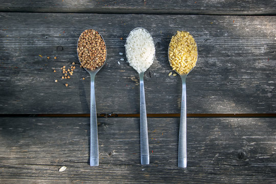 buckwheat, rice and bulgur in a tablespoon on a wooden background