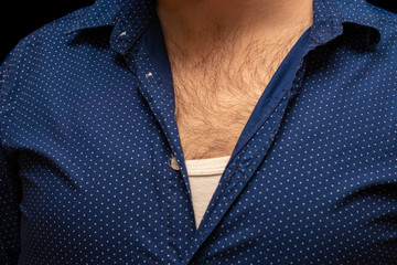 Several top bottuns unbottuned on a shirt of a man with hairy chest, blue european style