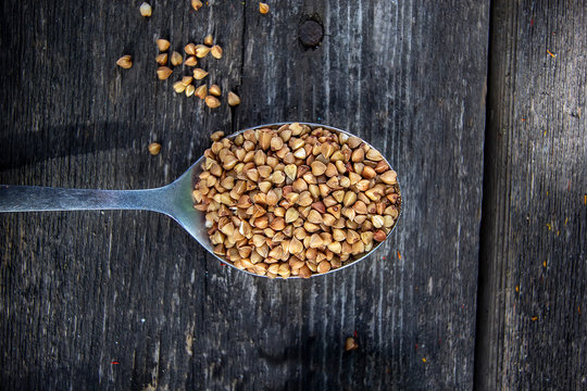 buckwheat in a tablespoon on a wooden background