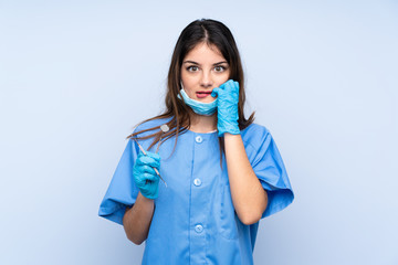 Woman dentist holding tools over isolated blue background nervous and scared