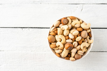 Various kinds of nuts (almonds, pistachios, peanuts, hazelnuts and cashews) in bowl on wooden table. Close up