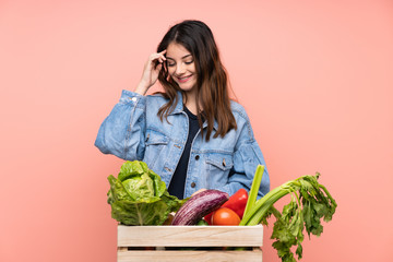 Young farmer woman holding a basket full of fresh vegetables laughing