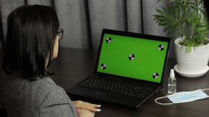 Woman have video call conference on laptop with green screen. Distance work