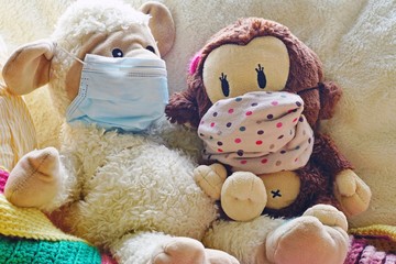 Two childrens plush stuffed animal toys earing a face mask during the COVID-19 pandemic