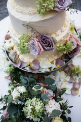 Wedding cake standing on the table. Around the flowers.