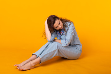 Young girl posing in pajamas on yellow background. Relax good mood, lifestyle and sleepwear concept.
