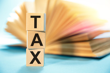 Wooden cubes with the abbreviation TAX on the background of an open book.