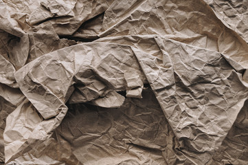 Grunge background from very strongly crumpled brown rough vintage paper. Texture surface made from recyclable materials.