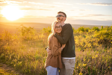 Young couple at sunset in nature, hugging and kissing