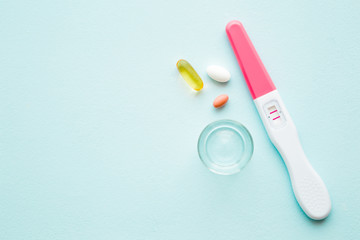 Pregnancy test with two stripes on pastel blue table background. Positive result. Receiving...