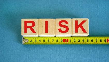 'Risk' word on cubes arranged behind the ruler on beautiful blue background. Concept.