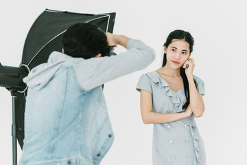 An Asian photographer photographing an Asian model in a photo studio. Are working professionally Viewed from the back of the photographer