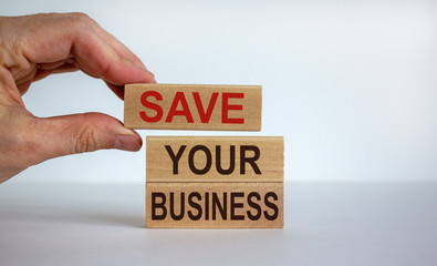 Male hand placing a block with word 'save' on top of a blocks tower with words 'your business'....