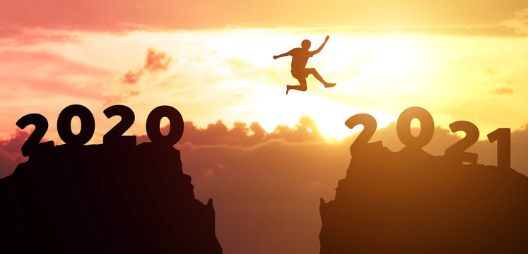 Jump  from 2020 to 2021 new year concept, silhouette of man jumping over barrier cliff and success with beautiful sunset background. Happy New Year 2021 use for web banner and advertisement.