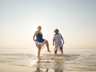 Two senior women having fun in the water at sea shore sunny day