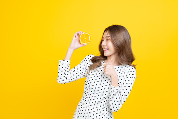 Beautiful Asian women smile happyness holding fresh orange slide with a yellow background.Squeeze Fresh oranges healthy fruits that are vitamin C.