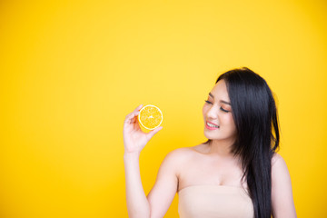 Beautiful Asian women smile happyness holding fresh orange slide with a yellow background.Squeeze Fresh oranges healthy fruits that are vitamin C.