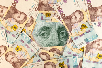 Benjamin Franklin eyes under a background of 1000 UAH or Ukrainian Hryvnia banknotes. Financial concept of Ukrainian currency rates.