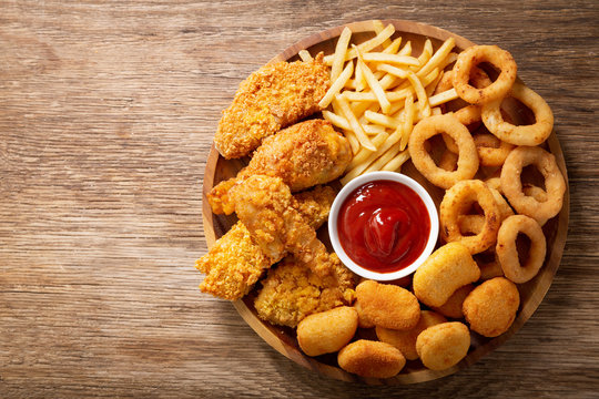 fast food meals : onion rings, french fries, chicken nuggets and fried chicken, top view
