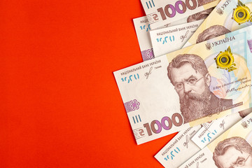 Background of 1000 UAH or Ukrainian Hryvnia banknotes in a Still Life layered in a side of red paper. Financial setup for mock-ups with your identity.