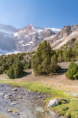 The beautiful mountain trekking road with clear blue sky and rocky hills and fresh mountain stream in Fann mountains in Tajikistan