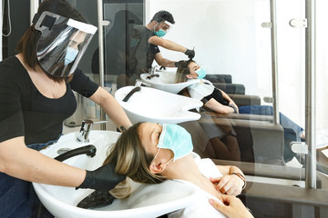 Servizio di lavaggio capelli dentro un salone da parrucchieri con tutte le disposizioni di protezione quali mascherine facciali, distanziamento , pannelli in plexiglass ecc